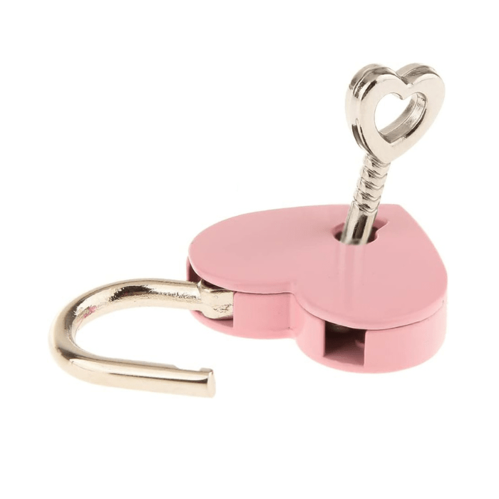 pale pink heart shaped lock with opened steel shackle and silver heart shaped antique key inserted in lock hole.