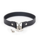 black pvc collar with metal loops on each end, linked together with a silver heart padlock, one key lying next to the lock