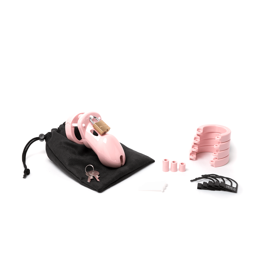 Fully assembled pale bubblegum pink CB-3000 chastity cage sitting on black cotton storage pouch with 2 metal keys to left. 3 white locking pins, 3 pink spacers, 4 pink U-rings and 5 black plastic locks lay displayed to the right.