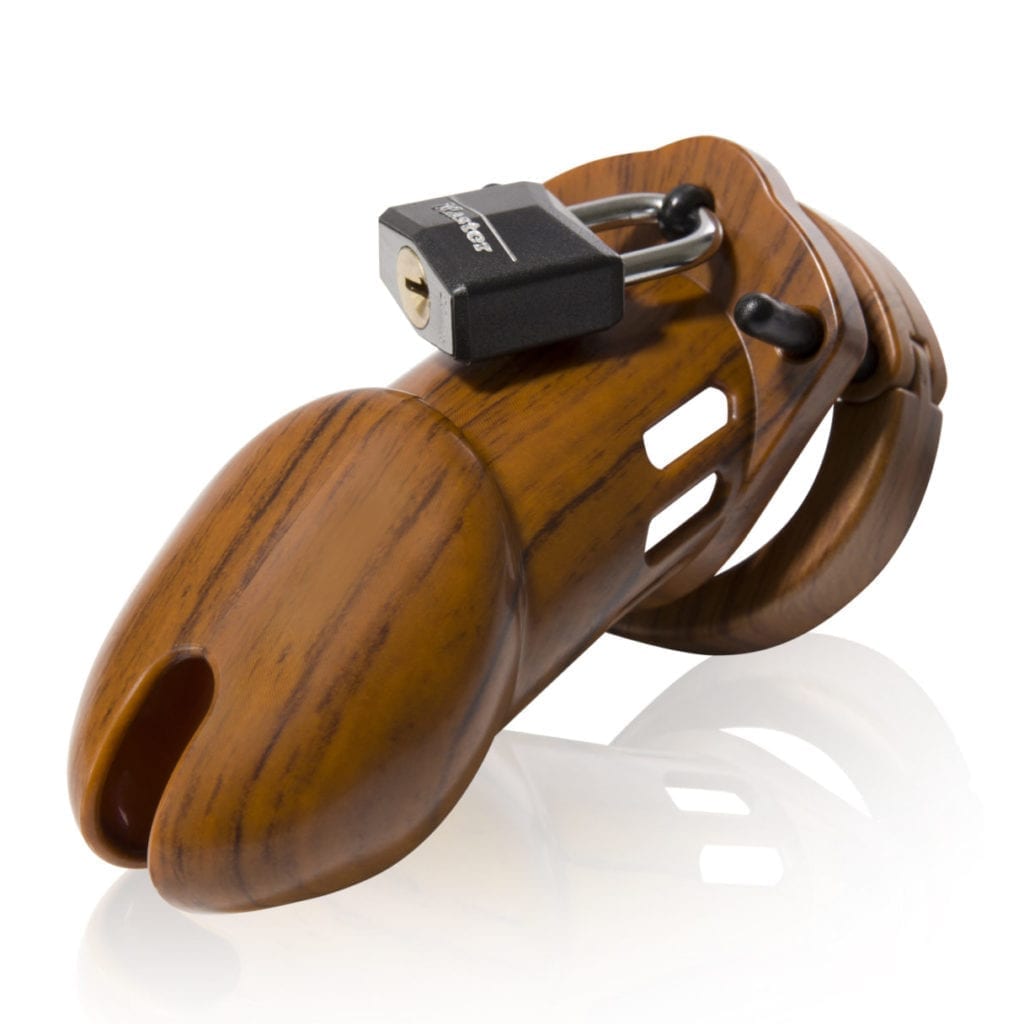 Front view, with tip angled to the left of a fully-assembled wood-grain finish CB-6000 penis chastity cage. Three black locking pins connect the wood-grain base ring to the wood-grain penis cage and a black coated padlock is secured through the hole on the center locking pin.