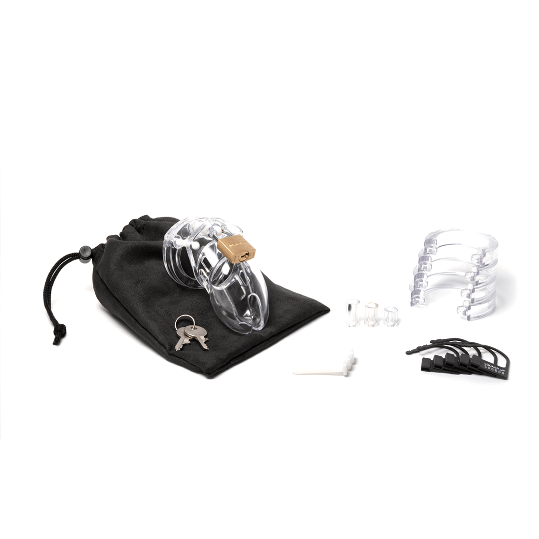 Fully-assembled clear CB-6000s chastity cage on a black cotton storage pouch with 2 metal keys to left. 3 clear spacers, 3 white locking pins, 4 clear stacked U-rings and 5 black plastic locks lay displayed on right.