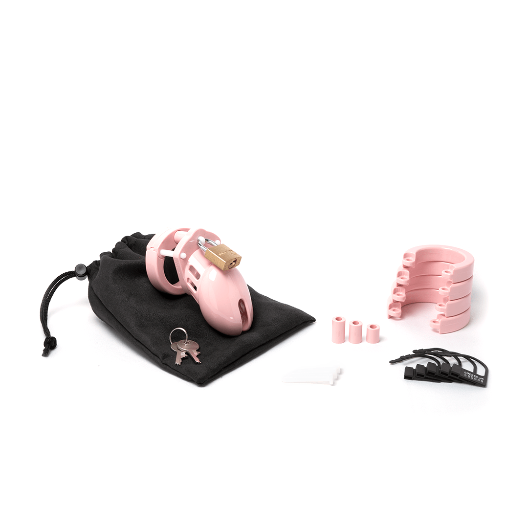 Fully-assembled pale pink CB-6000s chastity kit on a black cotton storage pouch with 2 metal keys, 3 pink spacers, 3 white locking pins, 4 pink U-rings and 5 black plastic.