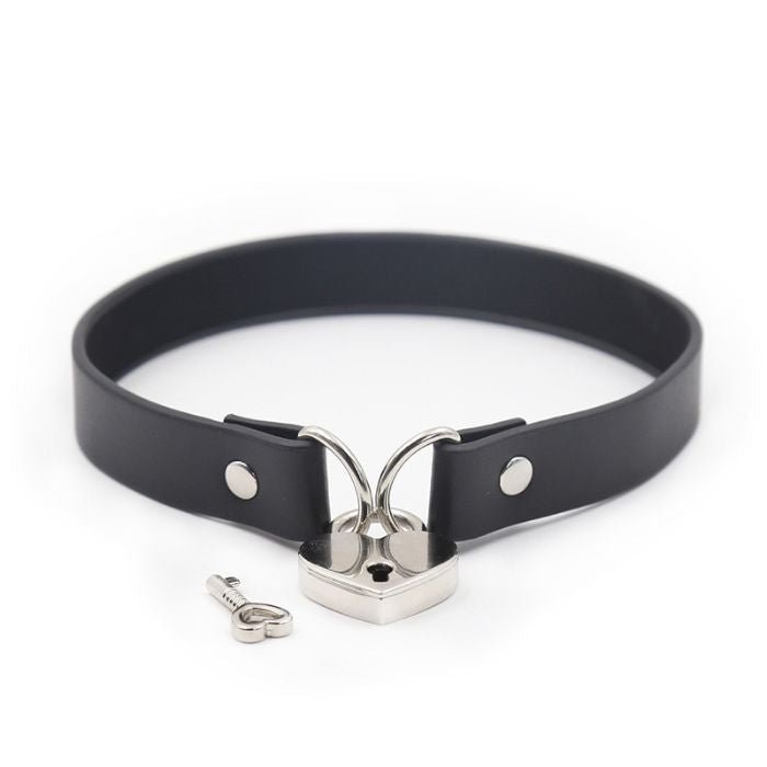 black pvc collar with metal loops on each end, linked together with a silver heart padlock, one key lying next to the lock
