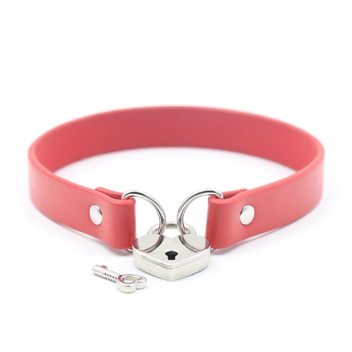 faded red pvc collar with metal loops on each end, linked together with a silver heart padlock, one key lying next to the lock