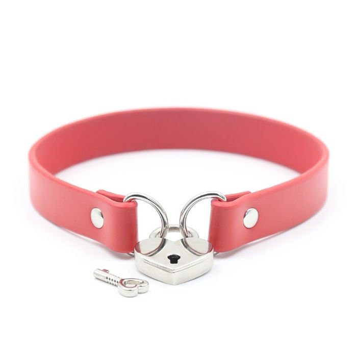 faded red pvc collar with metal loops on each end, linked together with a silver heart padlock, one key lying next to the lock